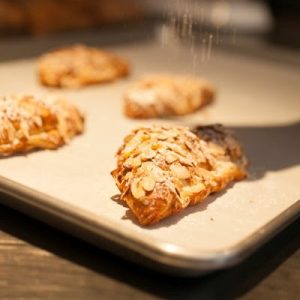 Almond Croissant, a flaky, golden pastry filled with almond paste and topped with sliced almonds, offering a sweet, nutty flavor and delicate, buttery layers.