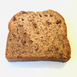 A slice of freshly baked Banana Bread, golden-brown with a moist, tender crumb and the perfect balance of sweet, ripe bananas in every bite.
