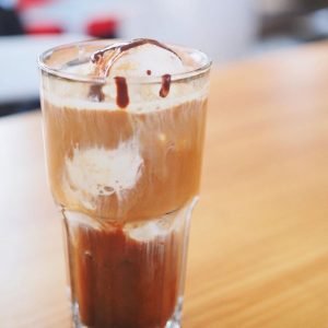 A rich coffee float topped with a scoop of creamy gelato in a tall glass.
