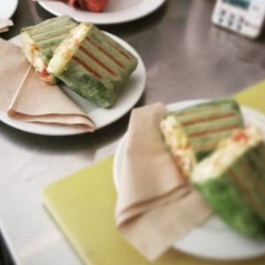 Egg wrap burrito filled with scrambled eggs, fresh veggies, and cheese, wrapped in a soft tortilla and served on a plate.