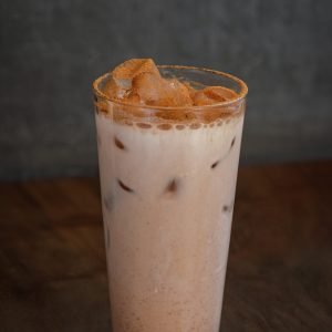 A refreshing glass of iced chai latte, with a blend of spiced chai tea and creamy milk, served over ice.