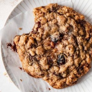 A freshly baked Oatmeal Almond Cranberry Cookie, with a golden-brown exterior and chewy center, featuring a delightful combination of oats, almonds, and dried cranberries.