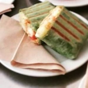 Sausage wrap with a savory sausage, fresh toppings, and sauce, wrapped in a soft tortilla and served on a plate.