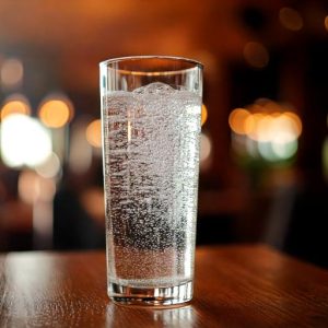 Chilled sparkling water bottle with condensation on a wooden table.